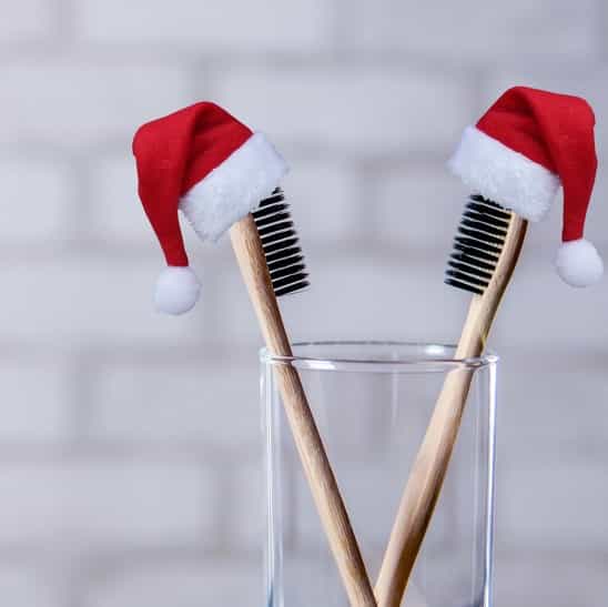 tooth brushes with santa hats in a glass