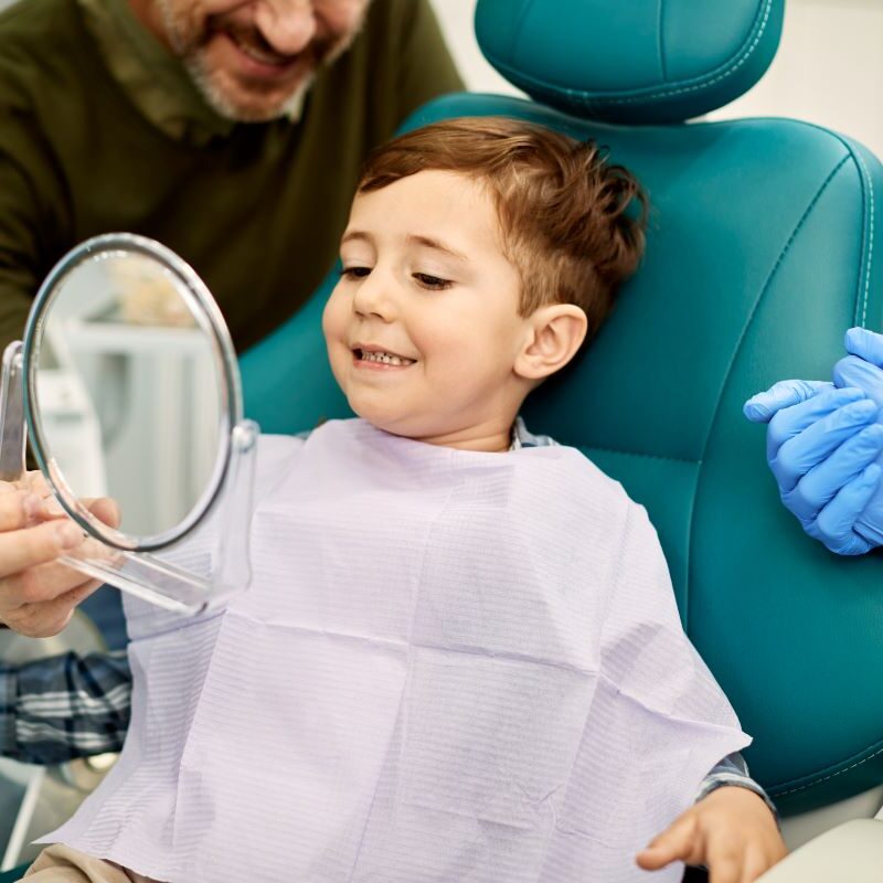 A young boy smiling while looking at his teeth in San Francisco, CA.